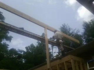 Carpenter setting a ridge beam over a new addition frame — Ice Dam Removal by Roofing Brothers in Rich Hill