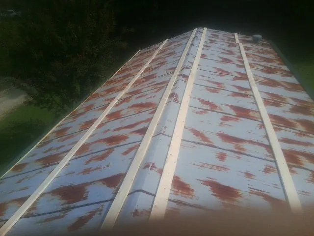 Rusted metal roof panels with new wood purlins before replacement — Storm Damage Roof Repair in Rich Hill by Roofing Brothers