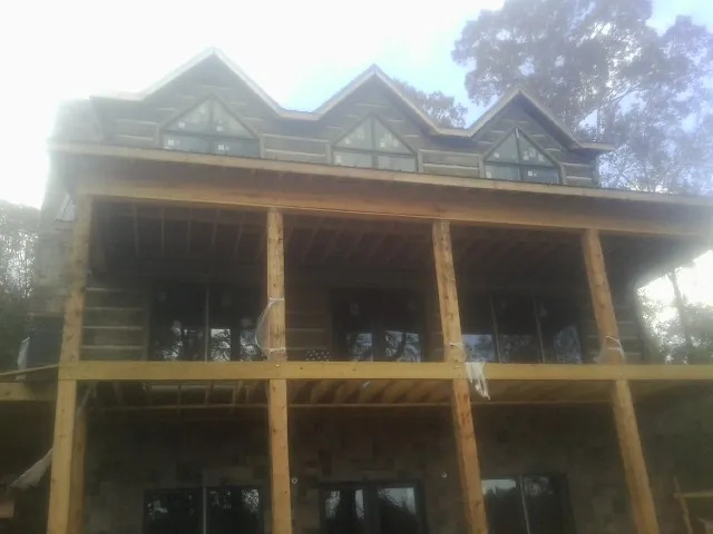 Dormers and porch framing on a large log home under construction — Roof Coating work by our crew in Rich Hill