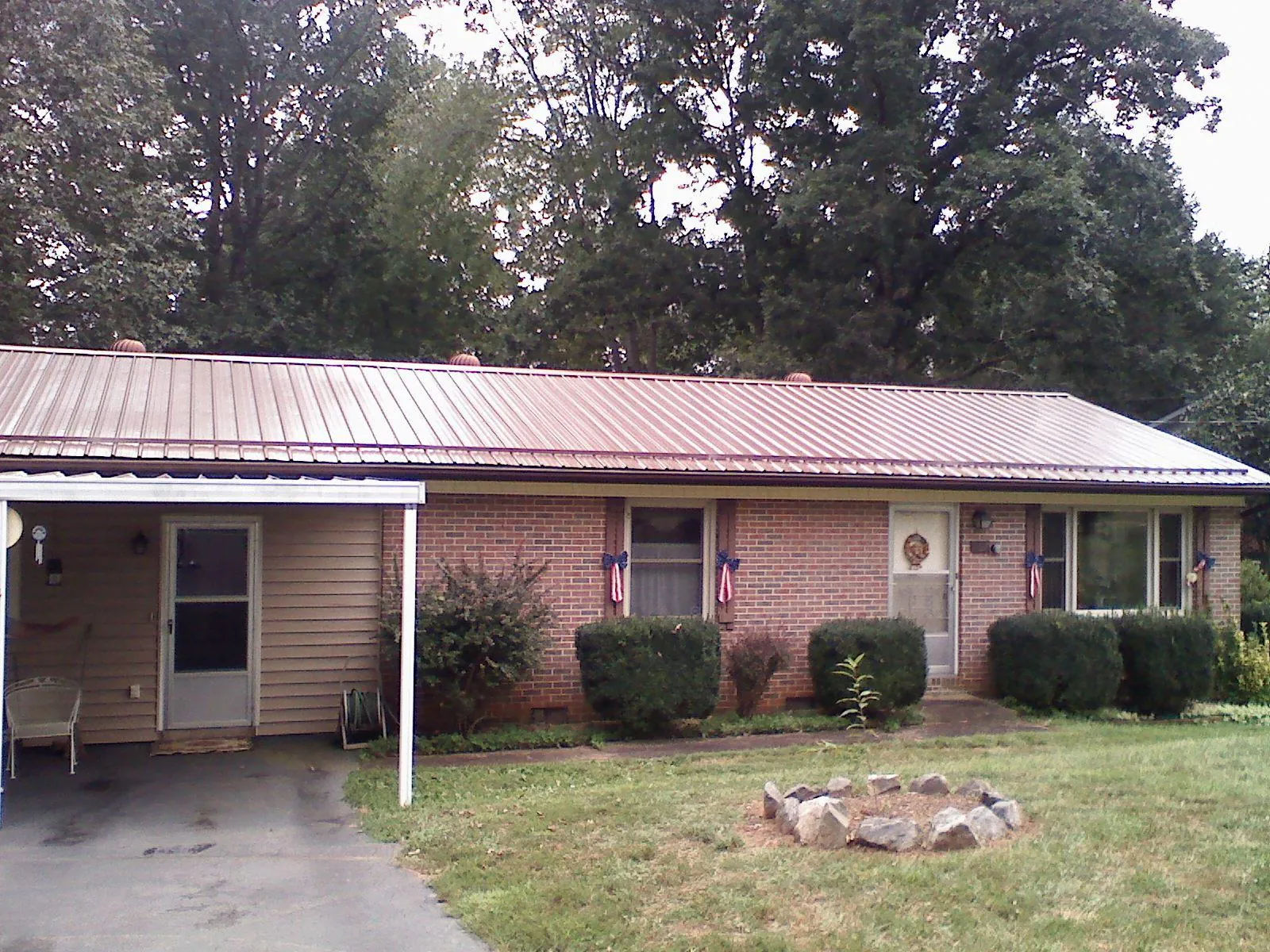 Bronze metal roof and carport on a brick ranch home — Roof Repair work by our crew in Rich Hill