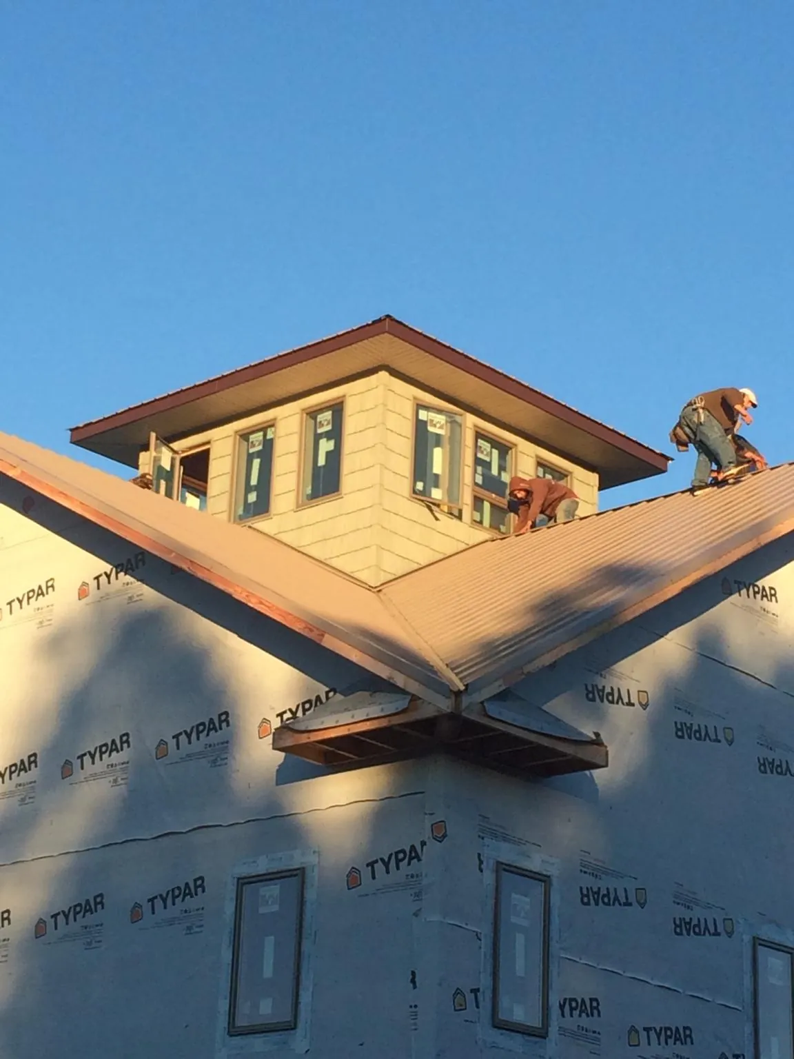Roofers working around a rooftop cupola on a new metal roof at sunset — Roof Waterproofing in Rich Hill by Roofing Brothers